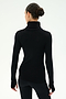 A person with dark hair in a bun is seen from behind, wearing the SPLITS59 Jackson Rib Full Length Turtleneck in Black/Creme and black pants, standing against a plain white background.