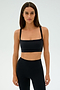 A woman wearing a SPLITS59 Monah Rigor Bra - Black and leggings stands against a plain background, epitomizing gym workouts as she gazes directly at the camera.