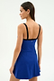 A woman faces away, wearing the SPLITS59 Monah Rigor Dress in cobalt and black, featuring a sleeveless design with black straps and a signature Monah silhouette against a plain light background.