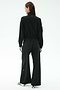 A person faces away, wearing the SPLITS59 Peaches Airweight Cargo Jacket in black stretch fabric and wide-leg pants with white text, plus white slide sandals with green stripes, against a plain light background.
