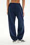 A person wearing the SPLITS59 Serena French Terry Oversized Sweatpant in Indigo/59, made from 100% cotton, and white sneakers stands on a white background with their hands relaxed by their sides.
