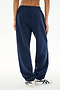 A person wearing the SPLITS59 Serena French Terry Oversized Sweatpant in Indigo/59, made from 100% cotton, and white sneakers stands on a white background with their hands relaxed by their sides.