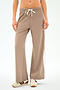 A person wears SPLITS59 Willow Airweight Wide Leg pants in Latte/White, paired with beige sneakers with brown stripes, standing against a plain white background.