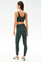 A woman faces away, wearing SPLITS59's Airweight Rib High Waist 7/8 leggings in Military with a matching sports bra and white sneakers, set against a plain white background.