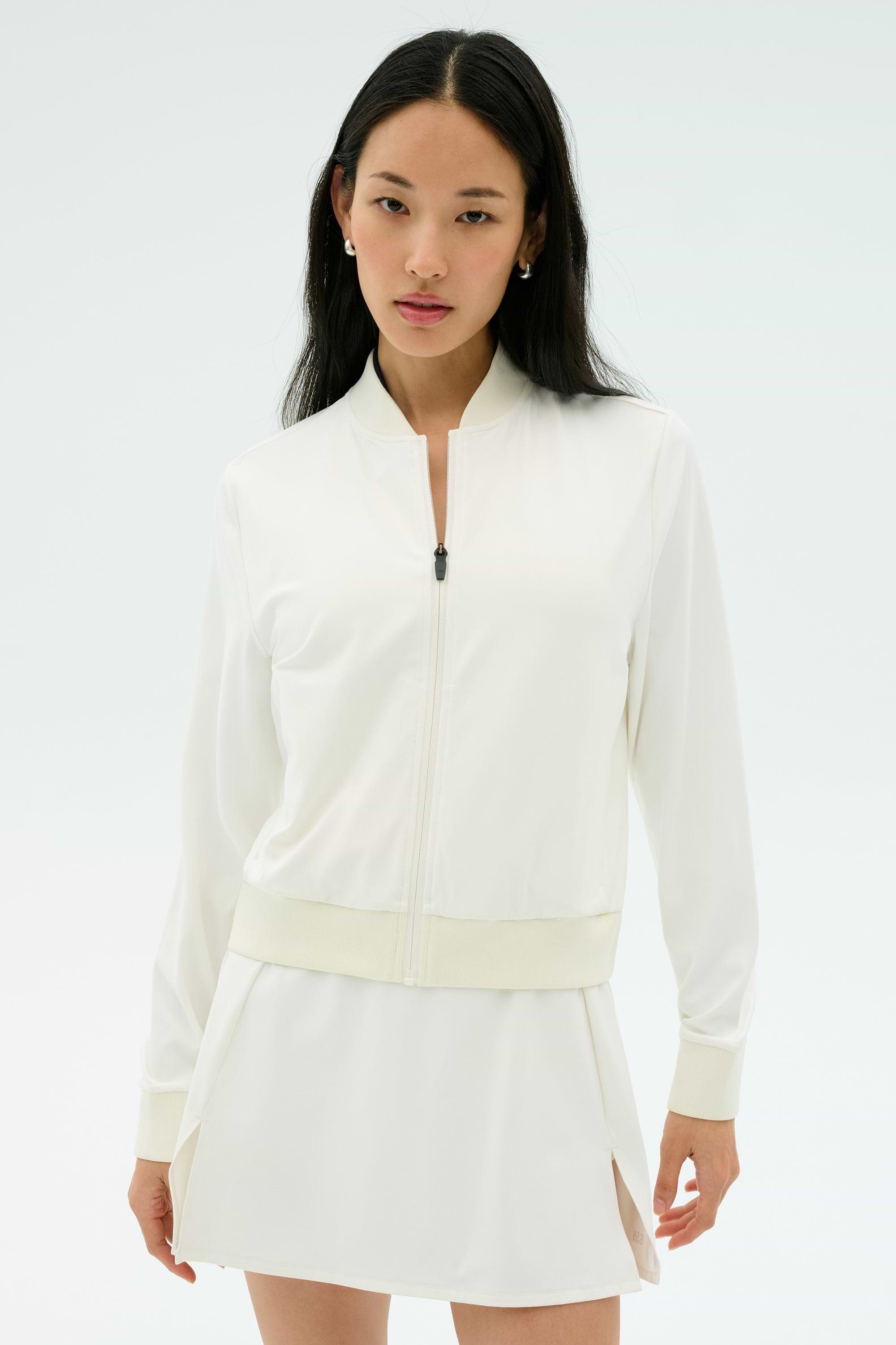 A woman wearing the SPLITS59 Airweight Bomber Jacket in white stands against a plain light background, looking at the camera.