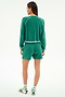 A woman faces away, wearing the SPLITS59 Brooks Fleece Sweatshirt With Stripe in Arugula/White, paired with matching shorts, striped socks, and sandals.