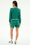 A woman faces away, wearing the SPLITS59 Brooks Fleece Sweatshirt With Stripe in Arugula/White, paired with matching shorts, striped socks, and sandals.