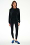 Woman stands against a white background, wearing the SPLITS59 Joy Velour Crewneck - Black with black leggings and blue sneakers.