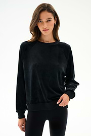 Woman wearing the SPLITS59 Joy Velour Crewneck - Black with black polyester spandex leggings, standing against a plain white background.