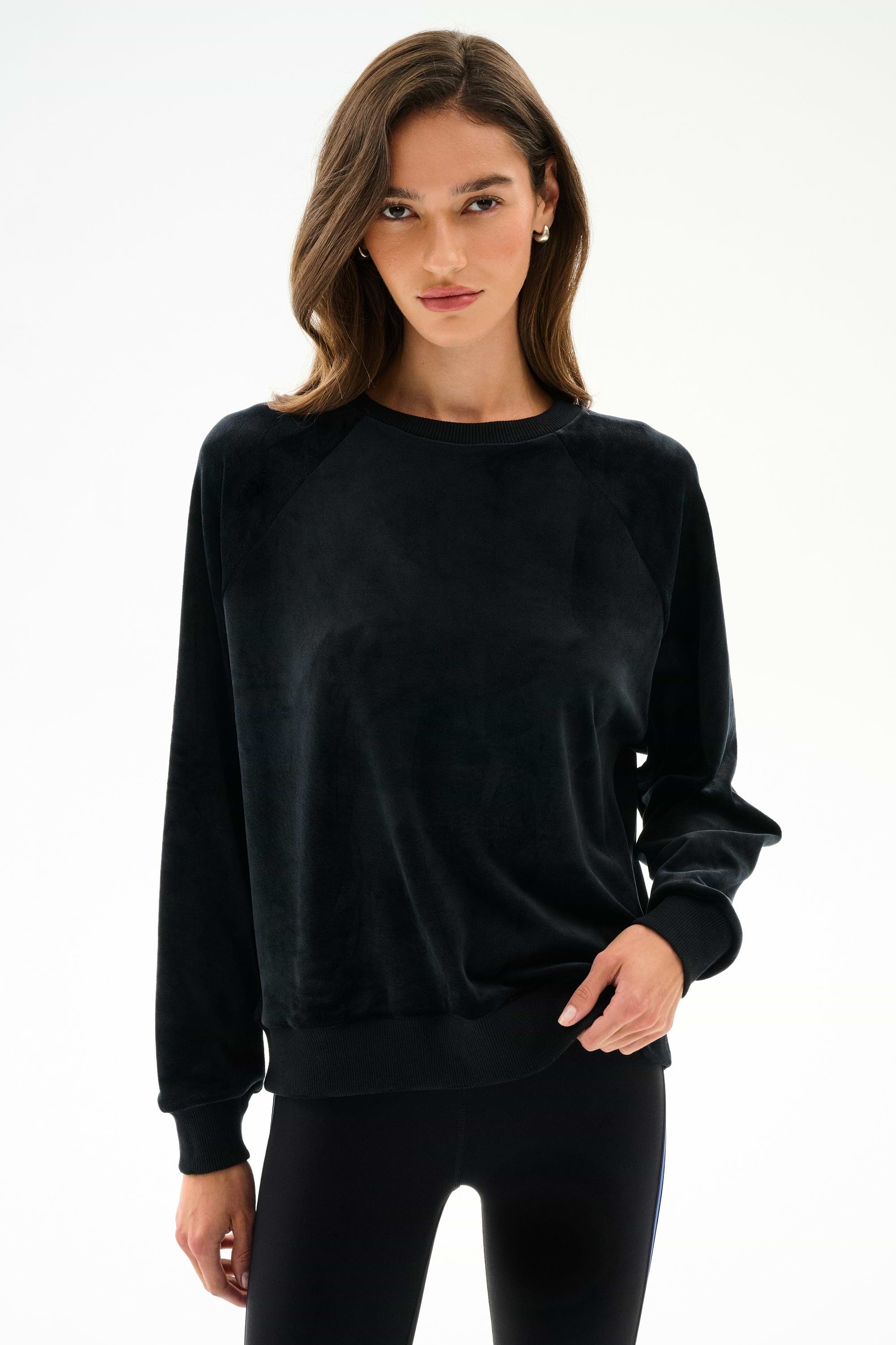 Woman wearing the SPLITS59 Joy Velour Crewneck - Black with black polyester spandex leggings, standing against a plain white background.