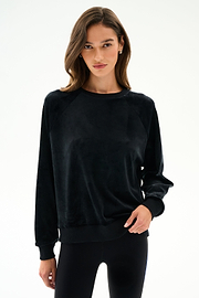 Woman wearing the SPLITS59 Joy Velour Crewneck - Black with black polyester spandex leggings, standing against a plain white background.