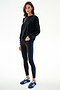 Woman wearing the Joy Velour Crewneck - Black by SPLITS59 and black leggings with a blue stripe, paired with blue Adidas sneakers.