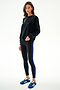 Woman wearing the Joy Velour Crewneck - Black by SPLITS59 and black leggings with a blue stripe, paired with blue Adidas sneakers.
