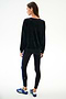 A person faces away, wearing the SPLITS59 Joy Velour Crewneck - Black, black leggings with a blue stripe, and blue Adidas sneakers on a plain white background.