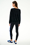 A person faces away, wearing the SPLITS59 Joy Velour Crewneck - Black, black leggings with a blue stripe, and blue Adidas sneakers on a plain white background.