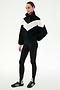 A person stands wearing the SPLITS59 Lottie Chevron Sherpa Full Zip Jacket in Black/Creme, crafted from soft polyester fleece, paired with black leggings with stirrups and black Adidas sneakers against a plain white background.
