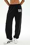 A person is wearing the SPLITS59 Serena French Terry Oversized Sweatpant in black with a “59” on the left thigh, paired with white sneakers featuring black accents, standing against a plain background; these sweatpants are made in Los Angeles.