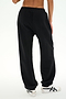 A person is shown from the waist down and viewed from the back, wearing SPLITS59 Serena French Terry Oversized Sweatpant in Black/59 with white sneakers, standing against a plain light background.