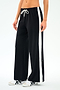 A person models the SPLITS59 Willow Airweight Wide Leg pants in Black/White, featuring buttery-soft fabric, wide legs, white side stripes, and a white drawstring, paired with white sneakers against a plain background.