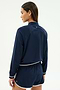 A person faces away, wearing the SPLITS59 Carrie Woven Nylon Jacket in Indigo/Lotus Red against a plain background.