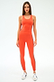 A woman faces forward against a white background, wearing the SPLITS59 Ella High Waist Airweight 7/8 jumpsuit in Valencia/Indigo with black side stripes and white sneakers.