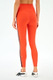A person is shown from the back in SPLITS59 Ella High Waist Airweight 7/8 leggings in Valencia/Indigo, featuring orange fabric with indigo side stripes, paired with white sneakers against a plain background.