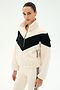 A person is wearing the SPLITS59 Lottie Chevron Sherpa Full Zip Jacket in Creme/Black, crafted from soft 100% polyester fleece with a black chevron stripe across the chest, paired with cream leggings featuring a black side stripe, standing against a plain white background.