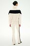 A woman stands facing away, wearing the SPLITS59 Lottie Chevron Sherpa Full Zip Jacket in creme and black, featuring a black horizontal stripe, paired with matching cream pants with black side stripes—all crafted from soft 100% polyester fabric for comfort and durability.
