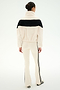 A woman stands facing away, wearing the SPLITS59 Lottie Chevron Sherpa Full Zip Jacket in creme and black, featuring a black horizontal stripe, paired with matching cream pants with black side stripes—all crafted from soft 100% polyester fabric for comfort and durability.