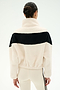 A person with dark hair in a bun models the SPLITS59 Lottie Chevron Sherpa Full Zip Jacket in Creme/Black—crafted from soft polyester fleece and featuring a black horizontal stripe—seen from the back, and paired with cream leggings that have black side stripes.