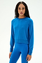 A woman with long dark hair stands against a plain white background wearing the SPLITS59 Brooks Fleece Long Sleeve Sweatshirt in Classic Blue, paired with matching blue leggings, both crafted from a soft modal spandex blend.