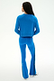A person stands with their back to the camera, dressed in the SPLITS59 Brooks Fleece Long Sleeve Sweatshirt in Classic Blue and matching blue flared pants with black side stripes, crafted from a soft modal spandex blend, paired with white shoes against a plain light background.
