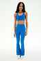 A woman stands against a white background wearing the SPLITS59 Raquel High Waist Supplex Flare leggings in Classic Blue/Indigo—a stylish, flared design crafted from 4-way stretch fabric for ultimate comfort—paired perfectly with white sneakers and a matching sports bra.