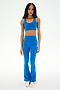 A woman stands against a white background wearing the SPLITS59 Raquel High Waist Supplex Flare leggings in Classic Blue/Indigo—a stylish, flared design crafted from 4-way stretch fabric for ultimate comfort—paired perfectly with white sneakers and a matching sports bra.