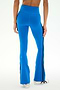 A person is shown from the back against a plain background wearing SPLITS59′s Raquel High Waist Supplex Flare pants in Classic Blue/Indigo, featuring black side stripes and paired with white sneakers. These high-waisted leggings offer 4-way stretch for optimal comfort and flexibility.