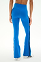 A person is shown from the back against a plain background wearing SPLITS59′s Raquel High Waist Supplex Flare pants in Classic Blue/Indigo, featuring black side stripes and paired with white sneakers. These high-waisted leggings offer 4-way stretch for optimal comfort and flexibility.
