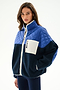 A woman wears the SPLITS59 Skylar Sherpa Jacket - Indigo/Cobalt, featuring a white zipper and chest pocket, standing against a plain white background.