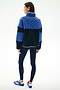 Woman faces away, wearing the SPLITS59 Skylar Sherpa Jacket - Indigo/Cobalt with navy leggings and blue Adidas sneakers, standing against a white background.