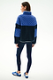 Woman faces away, wearing the SPLITS59 Skylar Sherpa Jacket - Indigo/Cobalt with navy leggings and blue Adidas sneakers, standing against a white background.