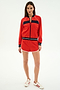 A woman faces forward wearing the SPLITS59 Carrie Woven Nylon Jacket in Lotus Red/Indigo, paired with matching shorts and white sneakers with red stripes, against a plain white background.