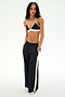 A person stands with hands in pockets, wearing a black nylon bralette, SPLITS59 Jordan Nylon Twill Tearaway pants in Black/Creme, and white sneakers against a plain white background.