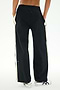 A person is seen from behind with hands in pockets, wearing SPLITS59's Jordan Nylon Twill Tearaway pants in Black/Creme, featuring white side stripes and crafted from a comfortable blend of nylon and spandex.