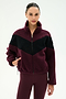 A woman stands against a plain light background wearing the SPLITS59 Lottie Chevron Sherpa Full Zip Jacket in Dark Cherry/Black, crafted from soft polyester, paired with matching maroon leggings.