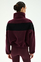 A person with dark hair in a bun is shown from the back against a plain background, wearing the SPLITS59 Lottie Chevron Sherpa Full Zip Jacket in Dark Cherry/Black—crafted from 100% polyester and featuring a black chevron stripe—paired with matching maroon leggings.