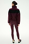 A woman stands facing away against a plain white background, wearing the SPLITS59 Lottie Chevron Sherpa Full Zip Jacket in Dark Cherry/Black—crafted from 100% polyester—with matching maroon leggings and black slip-on shoes.