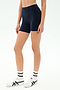 A person wears SPLITS59's Airweight High Waist Short in Indigo, a seamless tank workout top, white socks, and white sneakers with black stripes while standing against a plain white background.