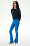 A person stands in a relaxed pose against a plain light background, wearing the SPLITS59 Brooks Fleece Long Sleeve Sweatshirt in indigo with raglan sleeve crewneck detailing, paired with bright blue flared pants featuring a side stripe and white sneakers. This effortlessly cool look is made in Los Angeles.