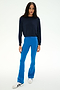 A person stands on a white background wearing the SPLITS59 Brooks Fleece Long Sleeve Sweatshirt in Indigo, paired with bright blue flared pants and white sneakers with black details. This long sleeve pullover is made in Los Angeles.