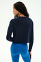 A person with long, braided hair is shown from the back against a plain white background, wearing the SPLITS59 Brooks Fleece Long Sleeve Sweatshirt in indigo and bright blue leggings. This stylish crewneck pullover features raglan sleeves and is made in Los Angeles.