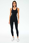 A woman faces forward against a white background, wearing SPLITS59's Ella High Waist Airweight 7/8 leggings in Black/White, a black sleeveless athletic top, and white sneakers.